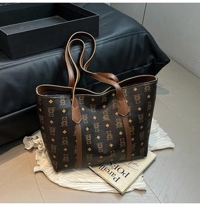 Close-up of a large brown tote bag featuring vintage bear monogram and leather straps