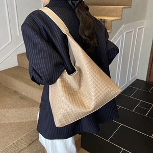 Borsa tote beige intrecciata indossata da modella con design minimalista ed ampio