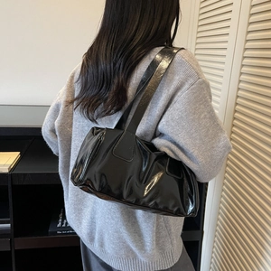 Bolso baguette retro de charol negro en modelo con un suéter de punto gris suave