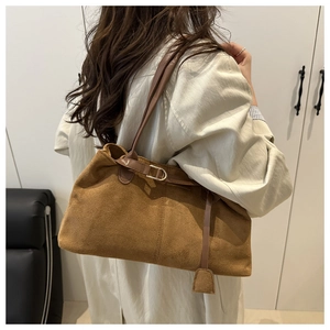 Detailed view of caramel suede tote bag featuring a leather buckle strap and gold hardware
