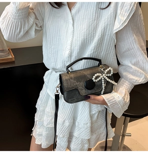 Détail du sac à bandoulière texturé vintage avec un grand nœud en perles sur le côté
