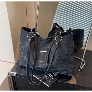 Detail of black tote bag featuring unique pleated texture fabric and silver metal rings