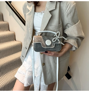 Détail du sac bandoulière gris foncé avec pendentif perle et fermoir magnétique