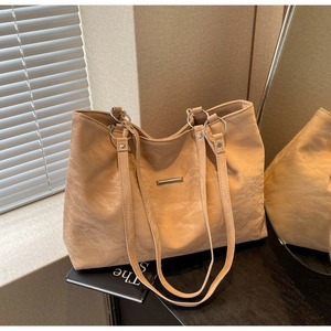 Detail view of large apricot tote bag featuring pleated texture and silver metal accents