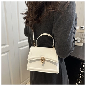 Detail of white structured handbag with golden double ring buckle and top handle strap