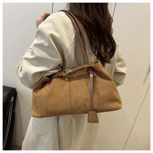 Brown frosted suede tote bag with long strap and decorative tag on model back view