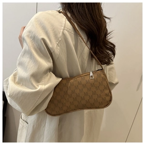 Detail of a brown shoulder bag with M-pattern texture and silver metal zipper closure