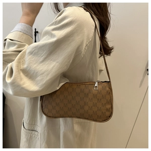 Detail of vintage brown baguette bag with monogram M pattern and silver zipper closure