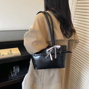 Dames zwarte leren shopper met een strik, getoond terwijl gedragen door model in trenchcoat