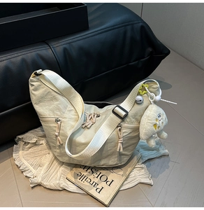 Detail of cream crescent crossbody bag with textured nylon and cute rabbit charm