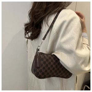 Close-up of retro brown monogram shoulder bag with leather tag on a trench coat