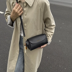 Sac bandoulière cylindrique noir chic avec finition texturée et porte-clés perlé