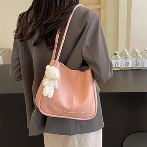 Pink soft leather square tote bag with cute white plush bear charm shown on shoulder