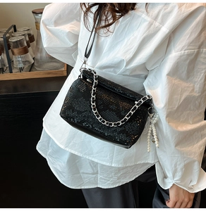 Detail of snake print crossbody bag with silver chain and pearl tassel on leather