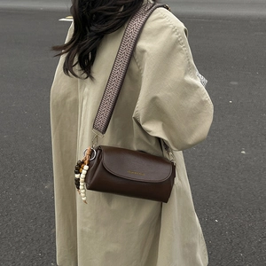 Sac à bandoulière cylindrique marron foncé minimaliste avec large sangle géométrique