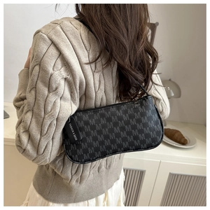 Detail of grey monogram baguette bag worn over the shoulder with a beige knit sweater