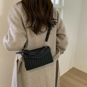 Retro black woven leather crossbody bag with gold hardware worn by a model
