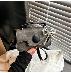 Détail du sac en denim gris avec boucle noire et breloque en perles en forme de nœud