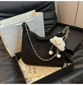 Détail du sac bandoulière en daim noir avec chaîne dorée et breloque nuage blanc en coffret