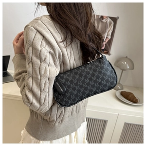 Chic black baguette bag with grey M-letter pattern shown in a minimalist home setting