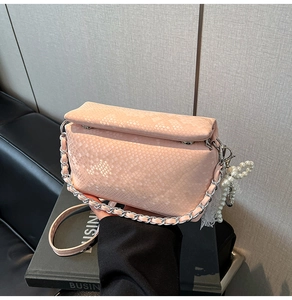 Detail of pink snakeskin pattern handbag with silver chain and pearl lace charm