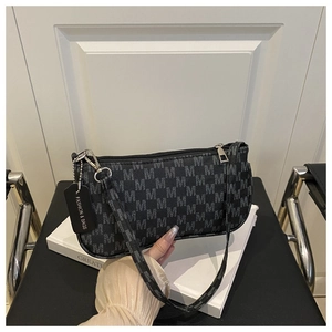 Close-up of black baguette bag with M-letter pattern, silver zipper, and fashion tag