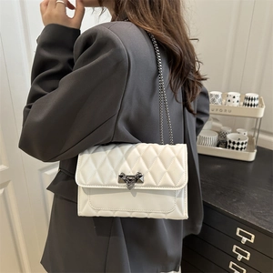 Chic white quilted crossbody bag with heart buckle and chain strap on a model