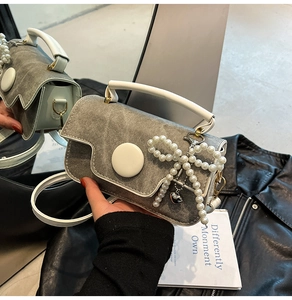Détail d'un sac bandoulière en denim gris avec nœud en perles et poignée blanche