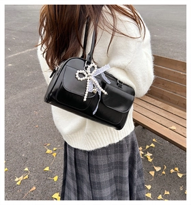 Detail of black leather underarm bag featuring pearl bows, lace, and heart charms