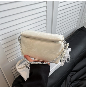 Close-up of snake skin texture leather bag with elegant lace bow and pearl charm