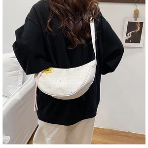 Détail du sac bandoulière demi-lune en toile avec motif damier jaune et étoiles
