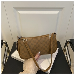 Close-up of brown baguette shoulder bag with M pattern print and silver zipper detail