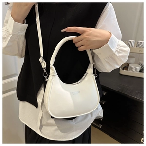 Detail of white moon-shaped shoulder bag with silver zipper and leather engraving