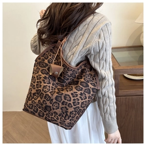 Detailed shot of large leopard print tote bag with brown leather trim and mini pouch
