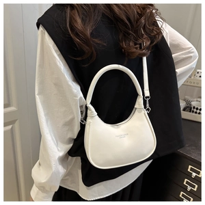 Minimalist white crescent shoulder bag with adjustable strap shown in home setting