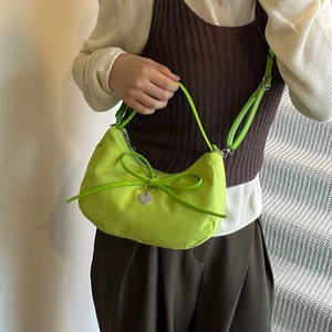 Neon green crescent bag with bow and heart pendant shown on model in street setting