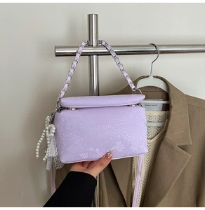 Detail of lavender snake pattern square bag with silver chain handle and pearl charm