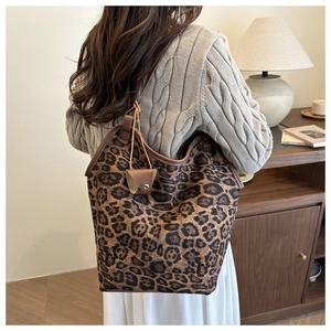 Macro detail of leopard print tote bag with brown leather trim and matching coin purse charm