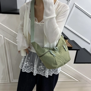 Avocado green crescent crossbody bag with nylon texture and wide woven shoulder strap