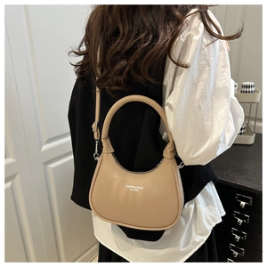 Detail view of a beige crescent moon leather shoulder bag worn over the shoulder
