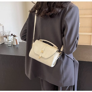 Sac bandoulière blanc cassé porté sur un blazer gris pour un look urbain décontracté