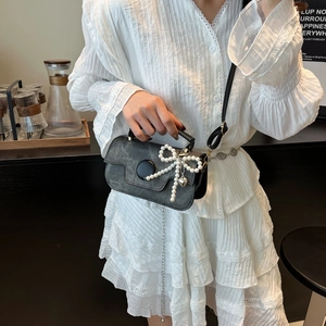 Sac bandoulière vintage gris foncé avec nœud perlé et pendentif cœur sur l'épaule