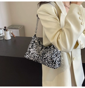 Close-up of a silver sequined shoulder bag with a metal chain strap worn by a model