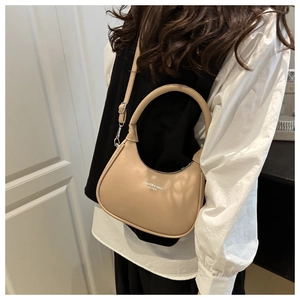 Detail of beige crescent bag showing leather texture and adjustable shoulder strap