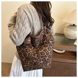 Close-up of leopard print tote bag with brown leather straps and side pendant detail