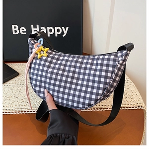 Gros plan du sac demi-lune à carreaux noir et blanc avec breloque étoile jaune et sangle