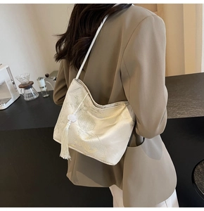 Silk shoulder bag with bamboo pattern and tassel detail in a minimalist cafe setting