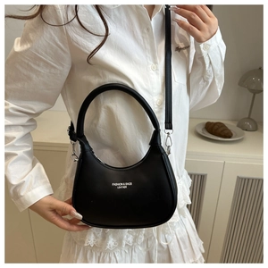 Detail of a black glossy hobo bag with adjustable strap shown in a lifestyle setting
