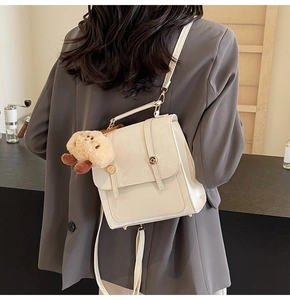 Chic cream white mini backpack on model's back featuring plush pendant and gold buckle