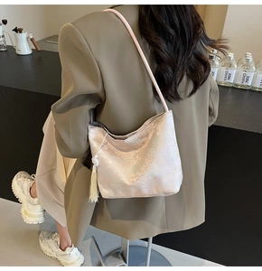 Close-up of champagne pink jacquard shoulder bag with white tassel on a model